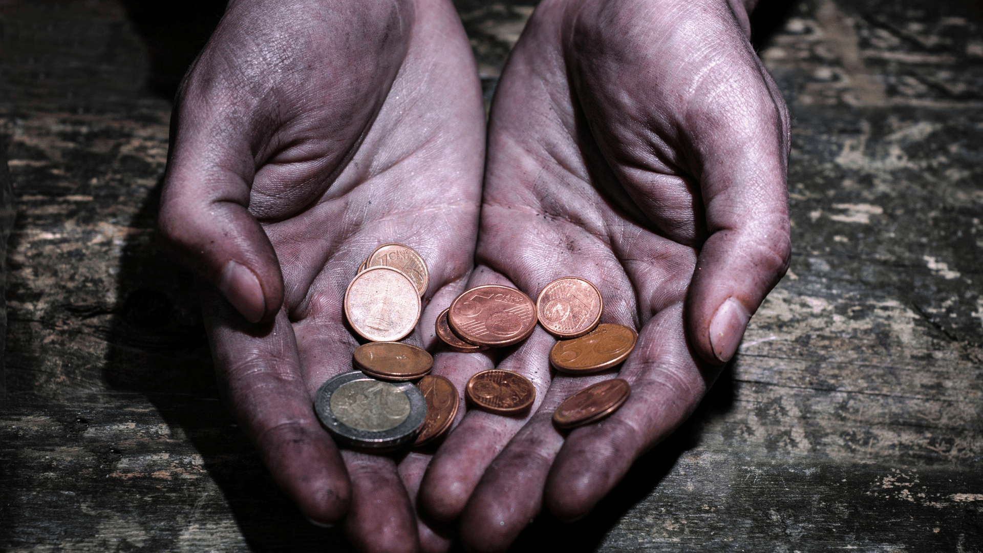 Dirty working hands holding small coins in their palms