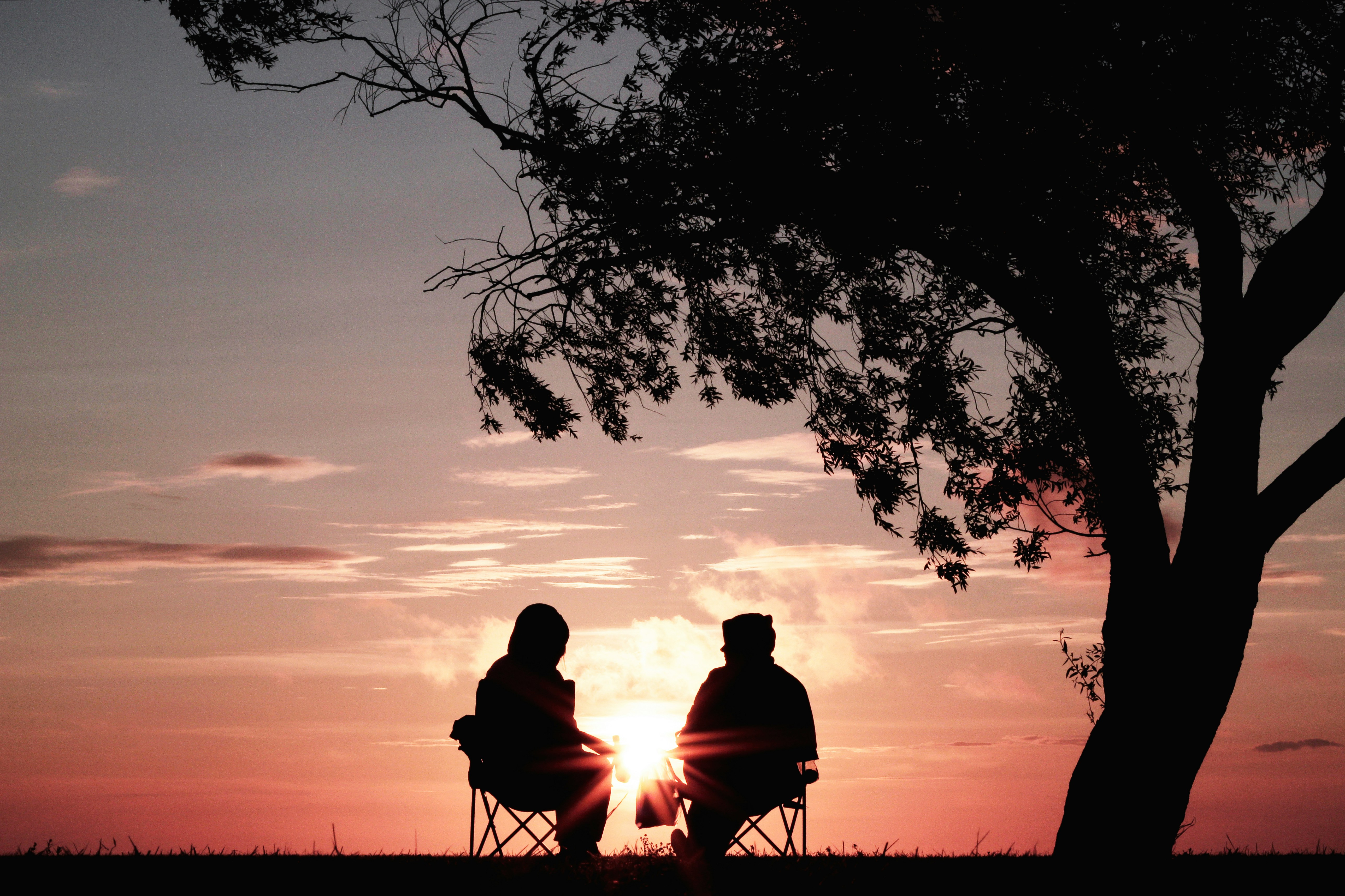 Two people seated enjoying the view of the sunset Two people seated enjoying the view of the sunset