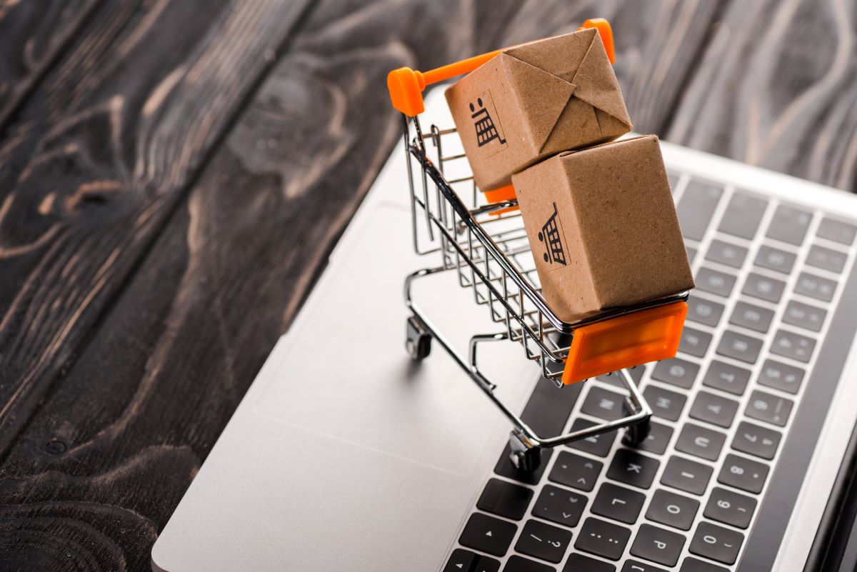 toy boxes in small shopping cart on laptop, e-commerce concept