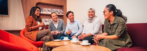 Orange Chairs And Coffee In A Business Lounge Setting With A Diverse Group Of 5 Young Adults