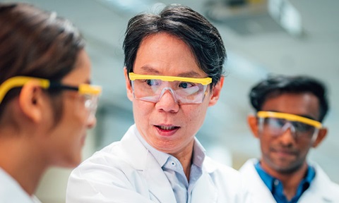 3 Scientists In Yellow Goggles In A Science Lab And Lab Coats (720x432px)